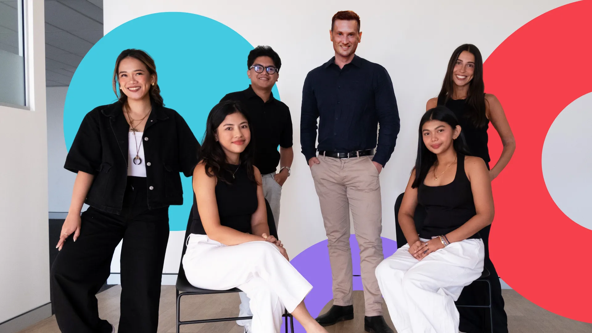 Six members of the MNO Ventures team in their office, four standing and two seated, smiling at the camera.